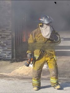 Bombero trabajando en sofocar incendio en casa de un señor de la tercera edad, quien falleció en el hospital.